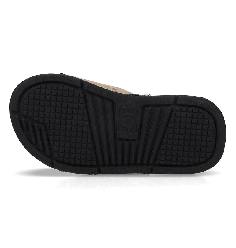 The image displays the black rubber sole of Kids' Bolsa Slides by DC Shoes, with a textured grip pattern and an embossed DC Shoes logo in the center.