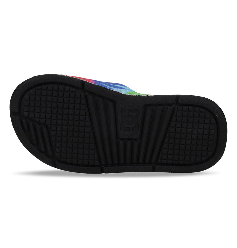 The image displays the black rubber sole of a Kids' Bolsa Slide by DC Shoes, featuring a textured pattern, a central logo, and the partially visible edge of the upper with a multicolored design.