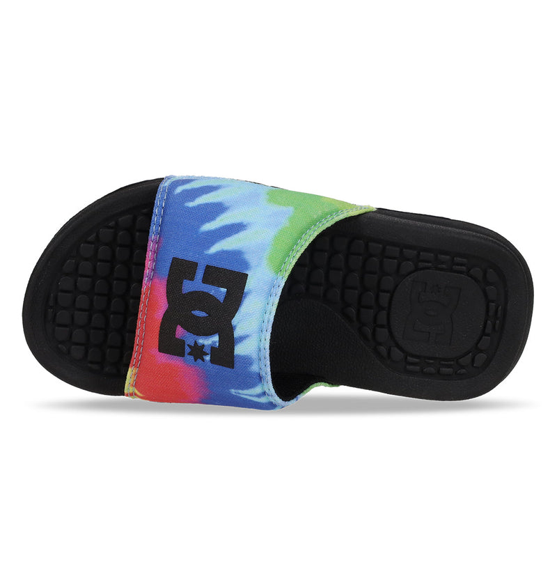 The DC Shoes Kids' Bolsa Slides feature a black sole, multicolored tie-dye strap with a black DC logo, a textured footbed, and an embossed DC logo near the heel—perfect comfortable slide sandals for kids.
