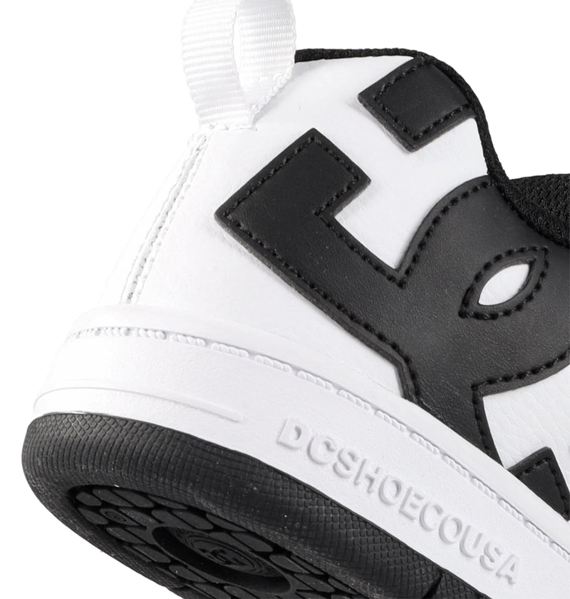 Close-up of the heel of a Kids' Court Graffik Shoe by DC Shoes, showing a large black DC logo, white pull tab, DCSHOECOUSA embossed on the midsole, and a textured black sole designed for skate-inspired style.