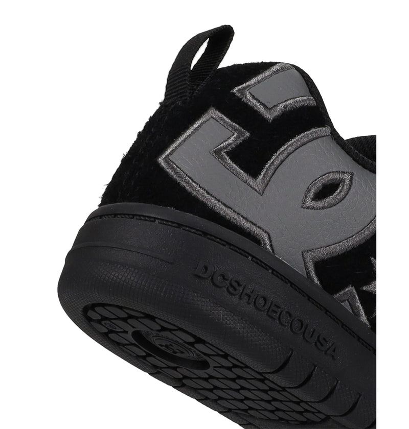 Close-up of the heel and sole of Kids' Court Graffik Special Edition Shoes by DC Shoes, featuring a large grey DC logo on the side and DCSHOECOUSA embossed on the black rubber sole.
