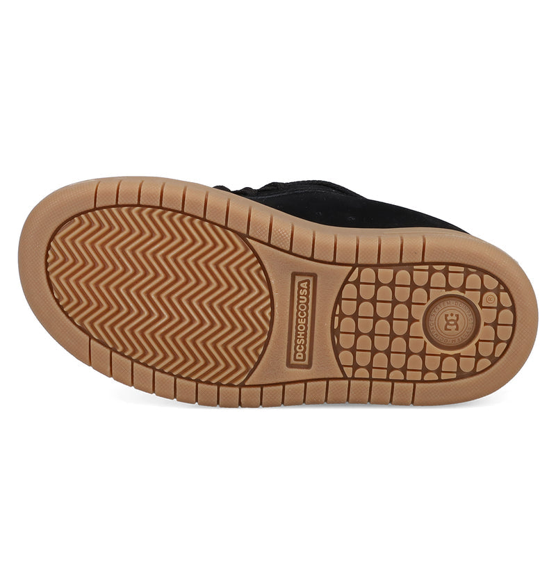 The image displays the gum sole of a black DC Shoes Kids' Court Graffik sneaker, showcasing a herringbone tread, circular grip pattern, and the signature DC logo by the heel.