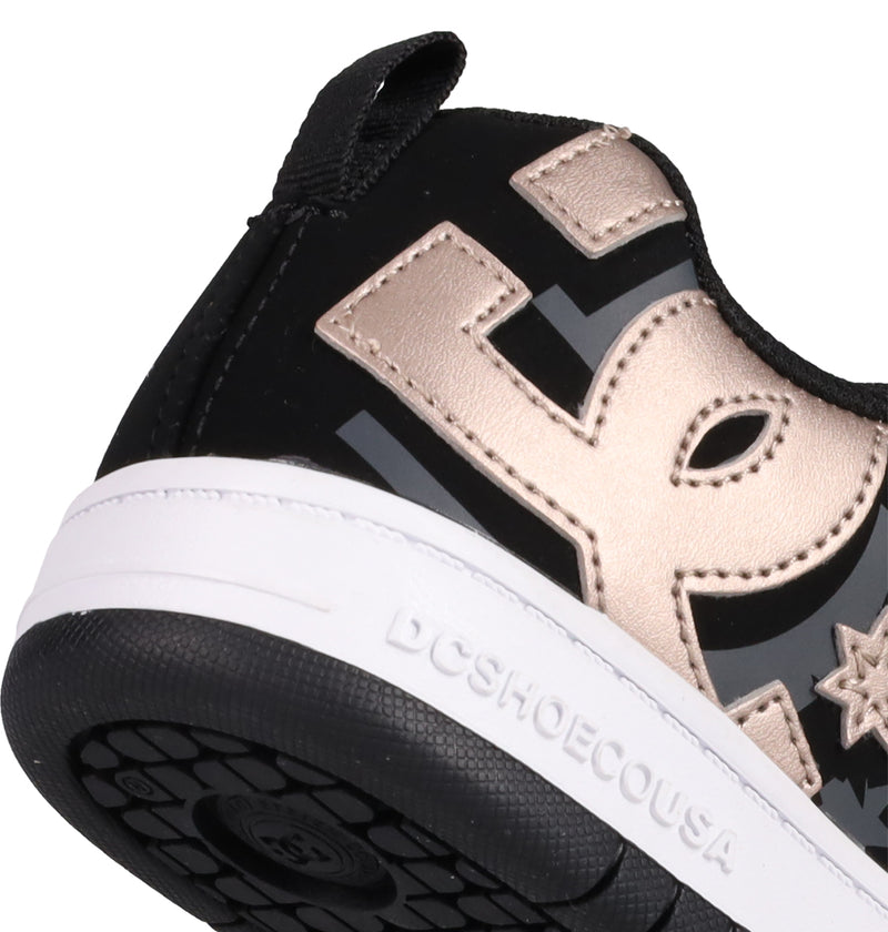 Close-up of the heel of DC Shoes Kids' Court Graffik Shoes in black and gold, featuring a puffy silhouette, white sole with DCSHOECOUSA embossed on the side, and a bold metallic gold DC logo.