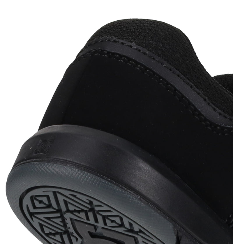 Close-up of the heel and sole of the Kids' DC Shoes Cure Elastic shoe by DC Shoes, featuring a textured tread pattern on the bottom and stitching details on the upper against a white background.