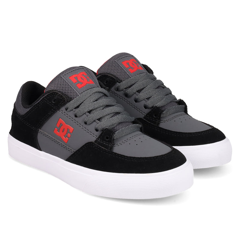 The DC Shoes Kids' Onyx Shoes feature a black and grey colorway with red DC logos, white rubber soles, grey laces, and black suede accents at the toe and heel—perfect for everyday style and comfort.