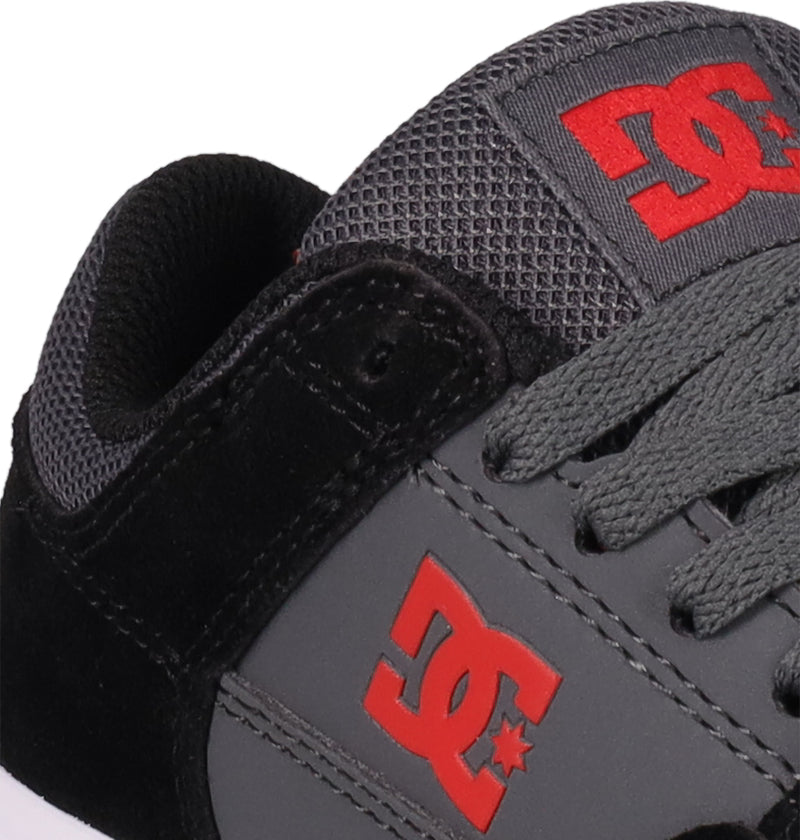 Close-up of DC Shoes Kids' Onyx, a black and gray sneaker with the red DC logo on the side and tongue, black laces, and mesh details—perfect for everyday wear.