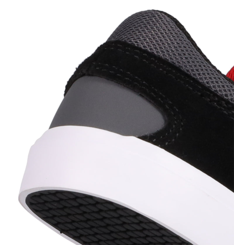 Close-up of the heel on DC Shoes’ Kids' Onyx Shoes, featuring a white sole, black suede upper, dark gray heel accent, and textured gray mesh by the ankle. The black-patterned outsole makes it an ideal everyday sneaker.