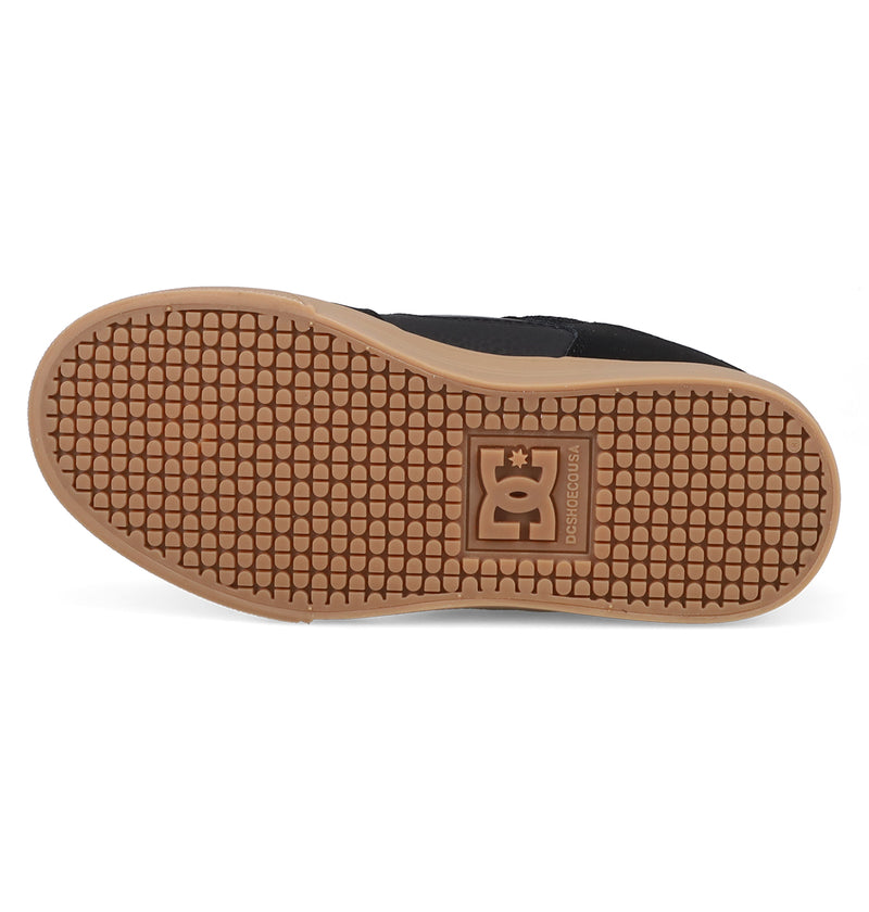 The image displays the sole of a black Kids' Pure Shoe by DC Shoes, featuring a light brown, textured waffle pattern and the DC Shoes logo embossed at the center, emphasizing its comfort for everyday use.