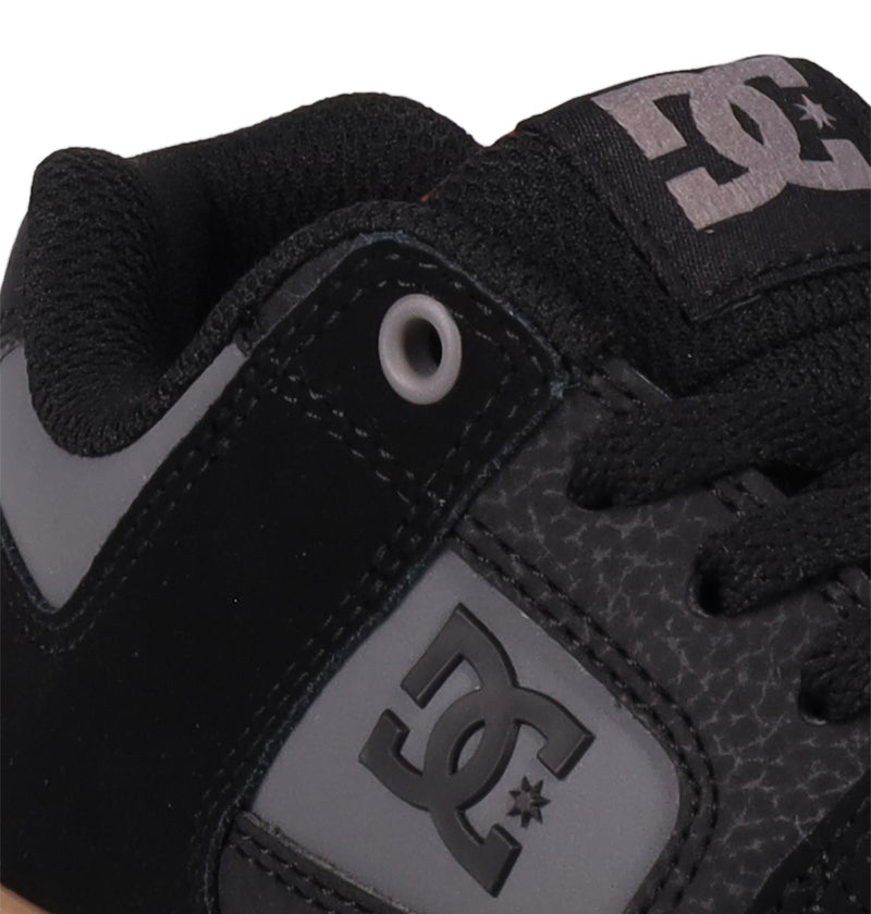 Close-up of black Kids' Pure Shoes by DC Shoes, featuring the DC logo on the side and tongue, black laces, and metallic eyelet detailing—versatile footwear that combines style and comfort for kids.