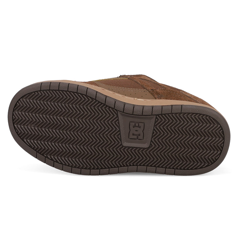 The image shows the sole of Kids' Stag Shoes by DC Shoes, featuring a brown color, herringbone tread pattern, and the DC logo in the center—emphasizing its skate culture roots.
