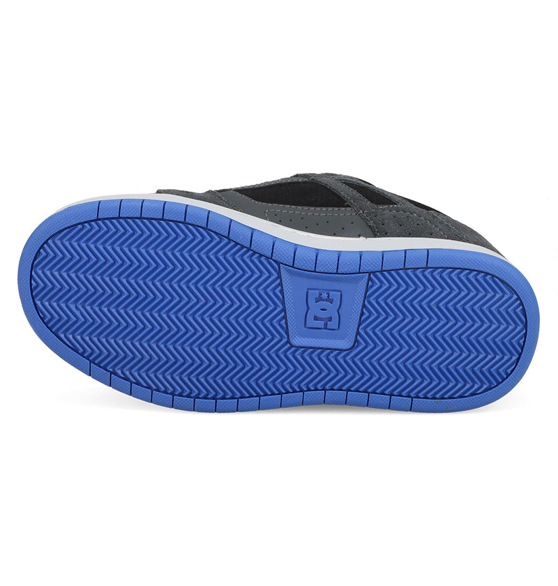 The image shows the bottom view of a black Kids' Stag Shoe by DC Shoes with a blue rubber sole, herringbone tread pattern, and central DC Shoes logo, highlighting its cupsole construction.