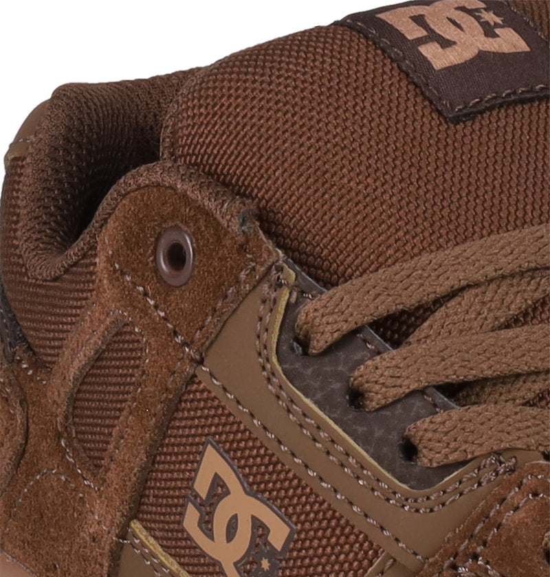 Close-up of Kids' Stag Shoes by DC Shoes, featuring the DC logo, textured suede and mesh, brown laces, cupsole construction, and stitched details—a tribute to classic skate culture.