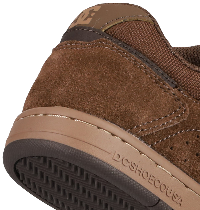 Close-up of the heel and side of brown suede Kids' Stag Shoes by DC Shoes, showing visible stitching, a skate-inspired design, durable cupsole construction, the DC Shoes logo, and a textured rubber outsole.