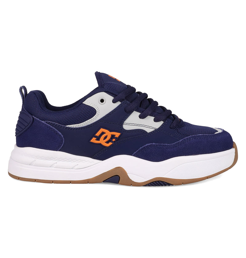 The Men’s DC Ascend S Shoes by DC Shoes feature a navy blue and white design, chunky white sole, orange accents, black laces, brown outsole, mesh/suede/synthetic materials, and the DC logo on the side for modern comfort and classic style.