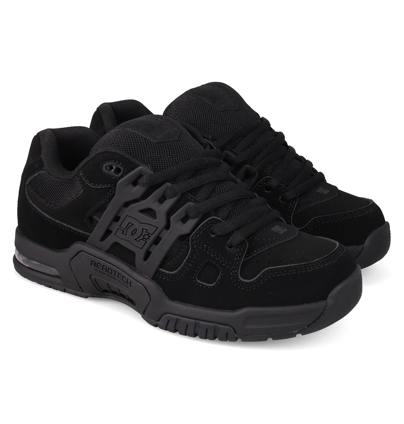 A pair of Men's AT-2 Shoes by DC Shoes featuring black mesh and suede uppers, thick airband outsoles, black laces, and a signature side plastic support labeled AEROTECH ventilation.