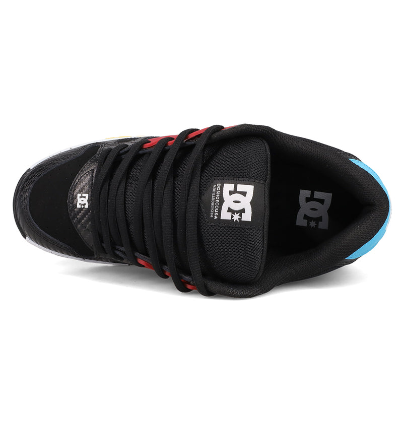 Top view of DC Shoes Men's AT-2: a black skate shoe with black laces, red and yellow accents, blue heel, and DC logo on tongue and insole. AEROTECH ventilation delivers breathable comfort for every ride.