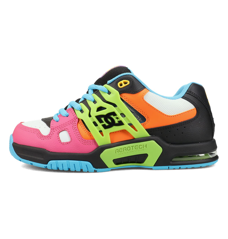 A colorful sneaker with a mix of pink, orange, yellow, blue, black, and green panels, blue laces, and a visible air cushion in the sole. The shoe features bold shapes and the DC logo on the side.