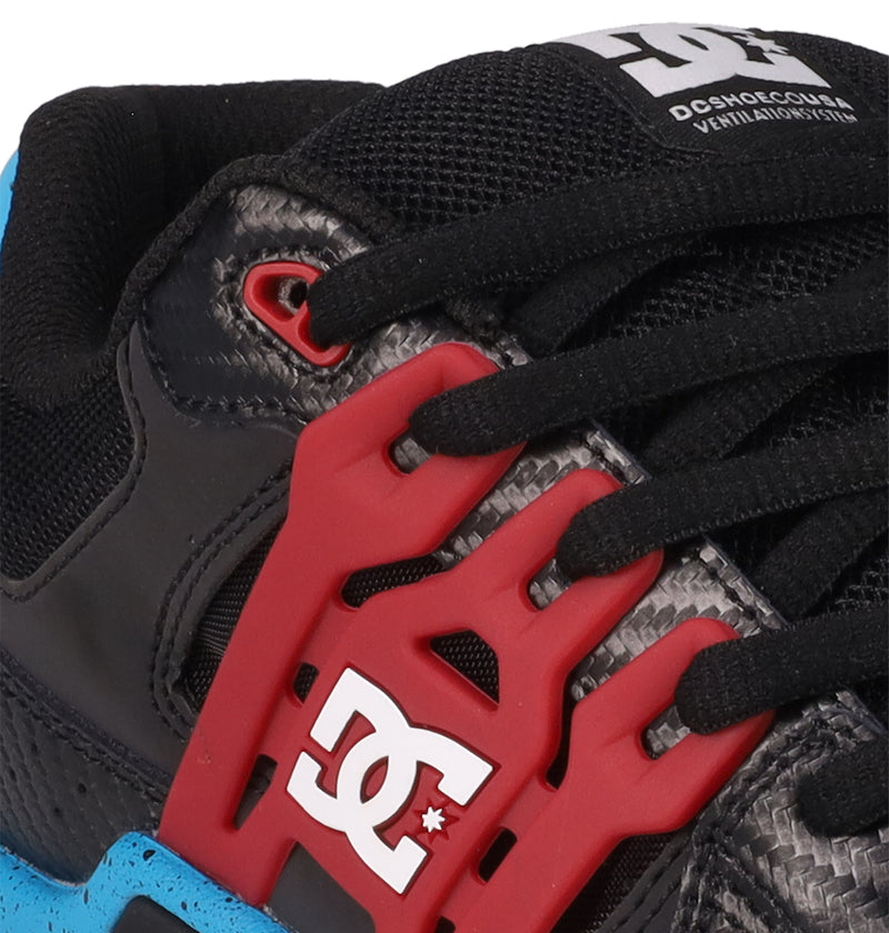 Close-up of the Men's AT-2 Shoes by DC Shoes in black and grey with black laces, a red plastic lace holder, white DC Shoes logo, branded tongue label, and a blue section on the sole for added cushioning.