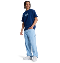 A person wears a navy DC Shoes t-shirt, white sneakers, and DC Shoes Men's Baggy Denim Carpenter Pant in a wide-leg fit, standing against a plain white background.