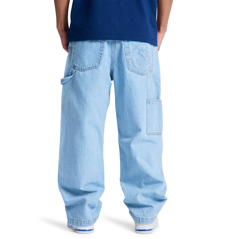 A person shown from the back against a plain white background wears DC Shoes Men's Baggy Denim Carpenter Pant in light blue with large pockets and a dark blue shirt.