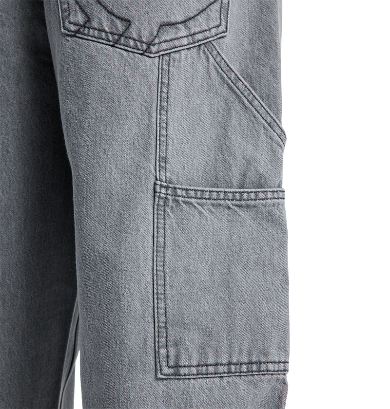 Close-up of the DC Shoes Men's Baggy Denim Carpenter Pant in gray, showing a large rectangular side pocket with visible stitching and part of another pocket above it, highlighting the signature baggy carpenter jeans style.