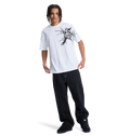 A person with braided hair wears a white graphic tee, black DC Shoes sneakers, and the Men's Baggy Denim Pant by DC Shoes, all set against a plain white background.