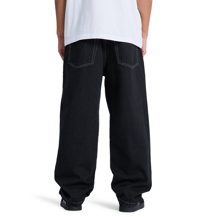 A person, seen from behind, wears a white t-shirt and DC Shoes Men's Baggy Denim Pant made from heavyweight denim, standing against a plain white background.