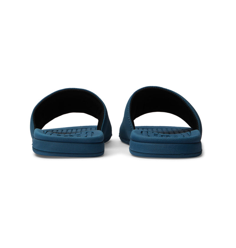 The Men's Bolsa Slides by DC Shoes are blue open-toe slides with textured footbeds and thick soles, shown from the back on a white background—ideal for slipping on after a skate session.