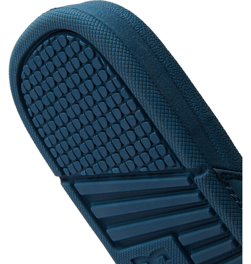 Close-up of the sole of DC Shoes Men’s Bolsa Slides reveals a textured grid pattern on the heel and horizontal ridges on the arch, with a hint of the logo—ideal for post-skate comfort.