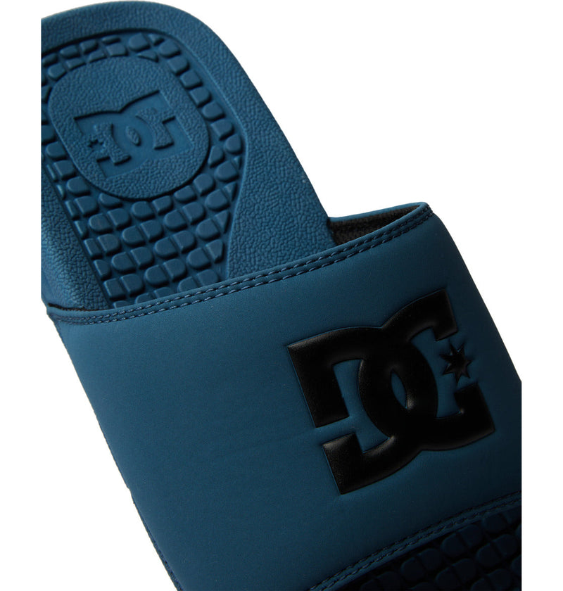 A close-up of the Men's Bolsa Slides by DC Shoes in blue, showcasing the black DC logo on the strap and embossed on the textured footbed—ideal for your next skate session.