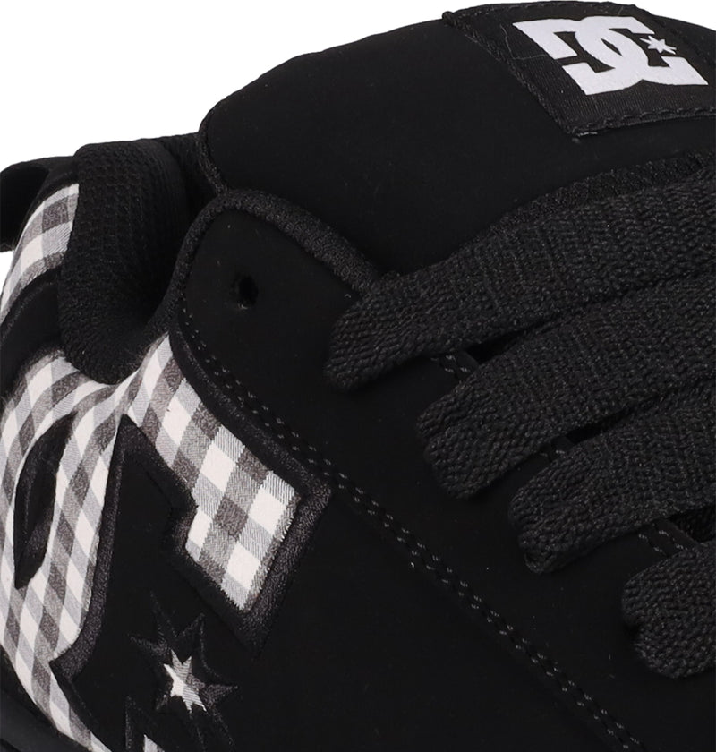 Close-up of the Men's Court Graffik Shoes by DC Shoes: black sneakers with black laces, a white and black checkered pattern, DC logos on the side and tongue, and the signature puffy silhouette.