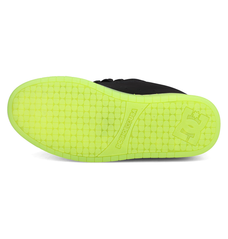 The image shows the sole of DC Shoes Men's Court Graffik SE Shoes in black, with a vibrant yellow-green textured bottom and the DC Shoes logo near the heel, emphasizing its trendy style.