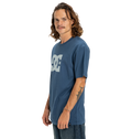 A man with long wavy hair and a mustache wears the Men's DC Star Tee by DC Shoes, showing his right forearm tattoo and gazing at the camera with a neutral expression against a white background.