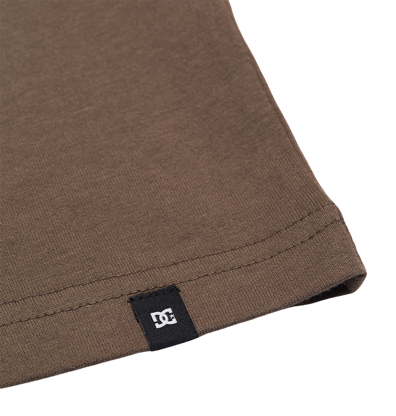 Close-up of the hem on the Men's DC Star Tee by DC Shoes, a relaxed fit brown shirt featuring a small black tag with the white DC logo sewn into the edge.