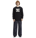 Young person with curly hair wears a black Men's DC Star Tee by DC Shoes, featuring bold graphics, paired with loose dark jeans and black sneakers, standing against a white background—ready to skate.