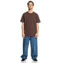 A man faces forward in a relaxed fit brown Men's DC Star Pocket Tee by DC Shoes, featuring a chest pocket, paired with loose blue jeans and black skate shoes against a plain white background.