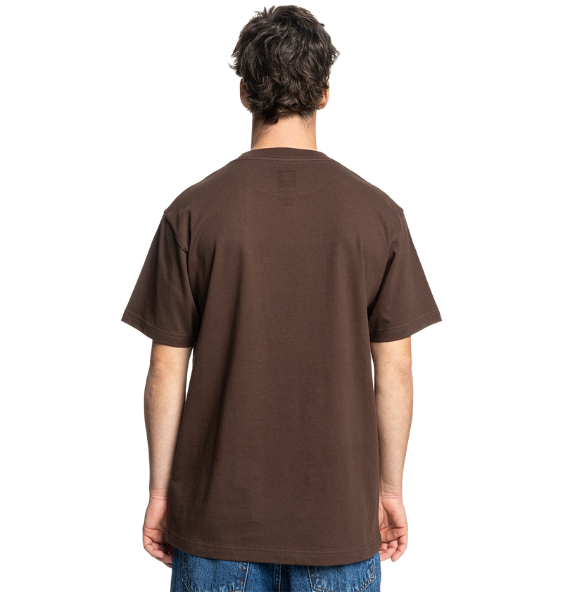A person with short, dark hair faces away, wearing the Men's DC Star Pocket Tee by DC Shoes—a relaxed fit brown skate shirt in soft cotton—paired with blue jeans against a light gray background.