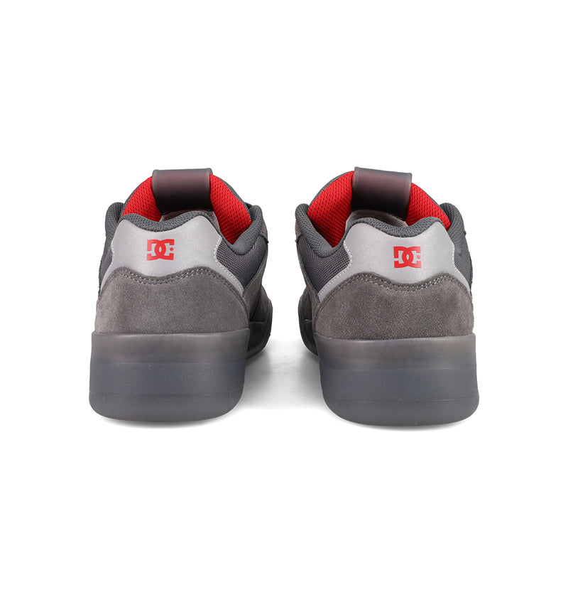 The Men's Fractal SE Shoes by DC Shoes are street-ready sneakers in grey and black suede, with red lining and a red DC logo on the heel, shown from the back.