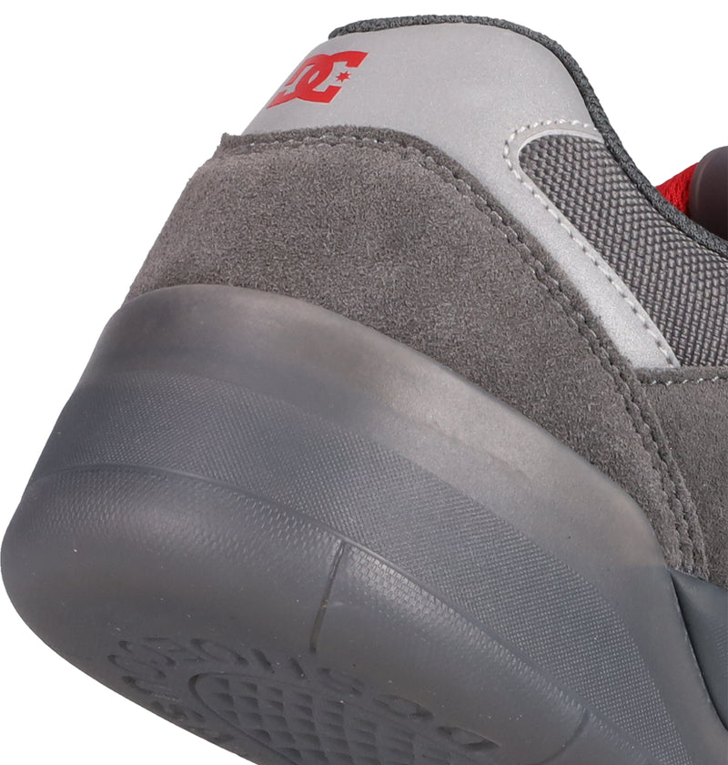 Close-up of the heel of a gray DC Shoes Men's Fractal SE skate shoe, featuring suede and mesh textures, a red DC logo on the silver collar, and a gray rubber sole for enhanced comfort and performance.