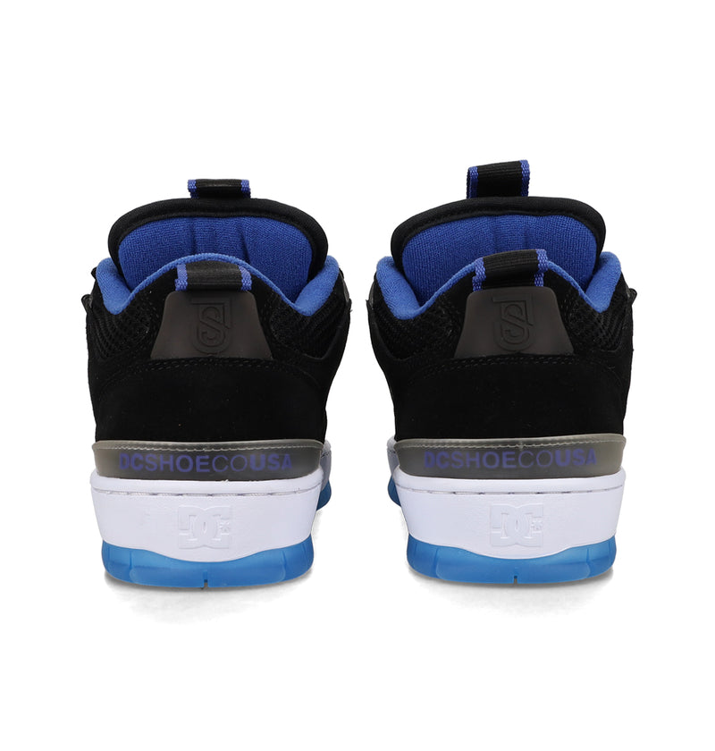 A pair of Men's JS-1 Shanahan Pro Skate Shoes by DC Shoes in black and blue, viewed from the back, displays the DCSHOECOUSA logo on the heel above a white and blue sole.