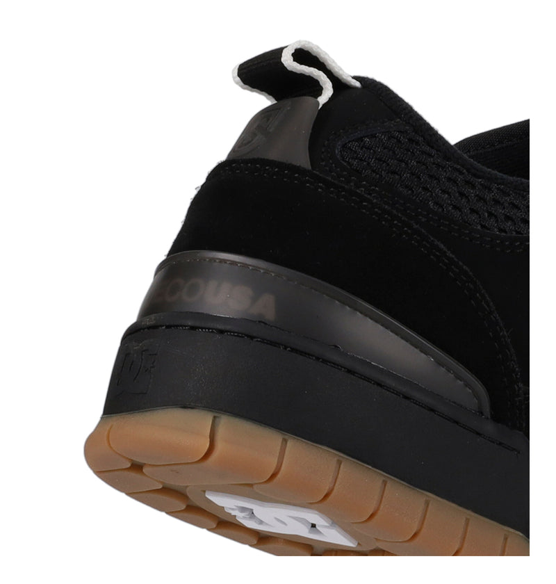 Close-up of a black shoe with a visible brand logo on a white background