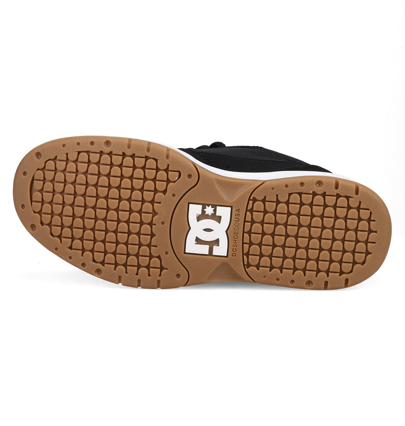 The image shows the sole of the Men's JS-2 Shanahan Pro Skate Shoe by DC Shoes, featuring a brown rubber grip and distinctive tread pattern with a white DC logo at the center, highlighting classic DC heritage.