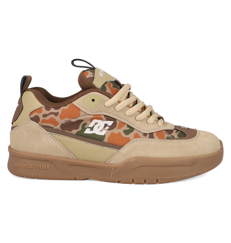The Men's JS 2 Shoes by DC Shoes feature a beige and tan suede upper, brown and green camo print, tan laces, a white DC logo on the side, and a brown rubber sole—blending DC heritage with John Shanahan’s unique style.
