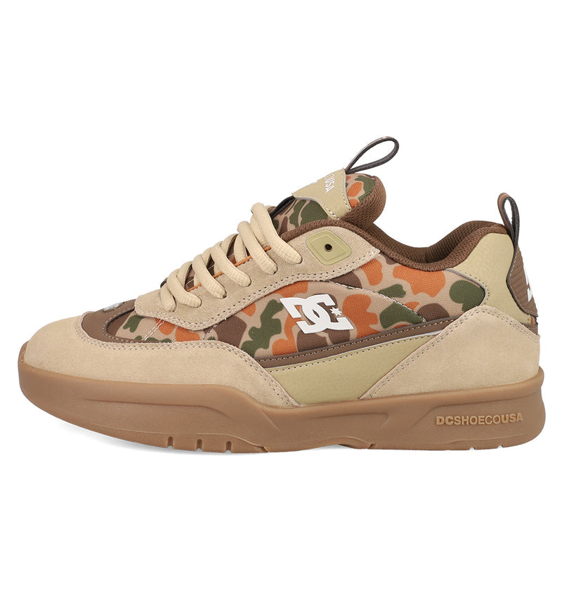The Men’s JS 2 Shoes by DC Shoes feature beige and brown tones, camouflage panels, a white side logo, tan suede accents, and a gum rubber sole—blending DC heritage style with modern design.