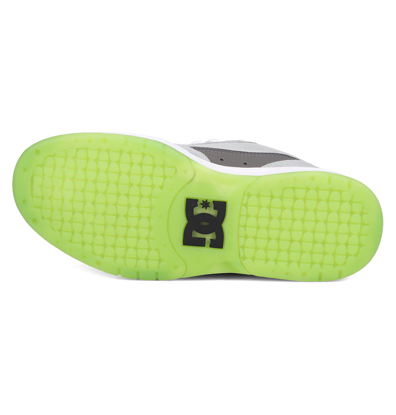 The image shows the sole of the Men's JS 2 Shoes by DC Shoes, featuring a translucent light green rubber grip with a black DC Shoes logo at the center, inspired by John Shanahan’s pro model and classic DC heritage.