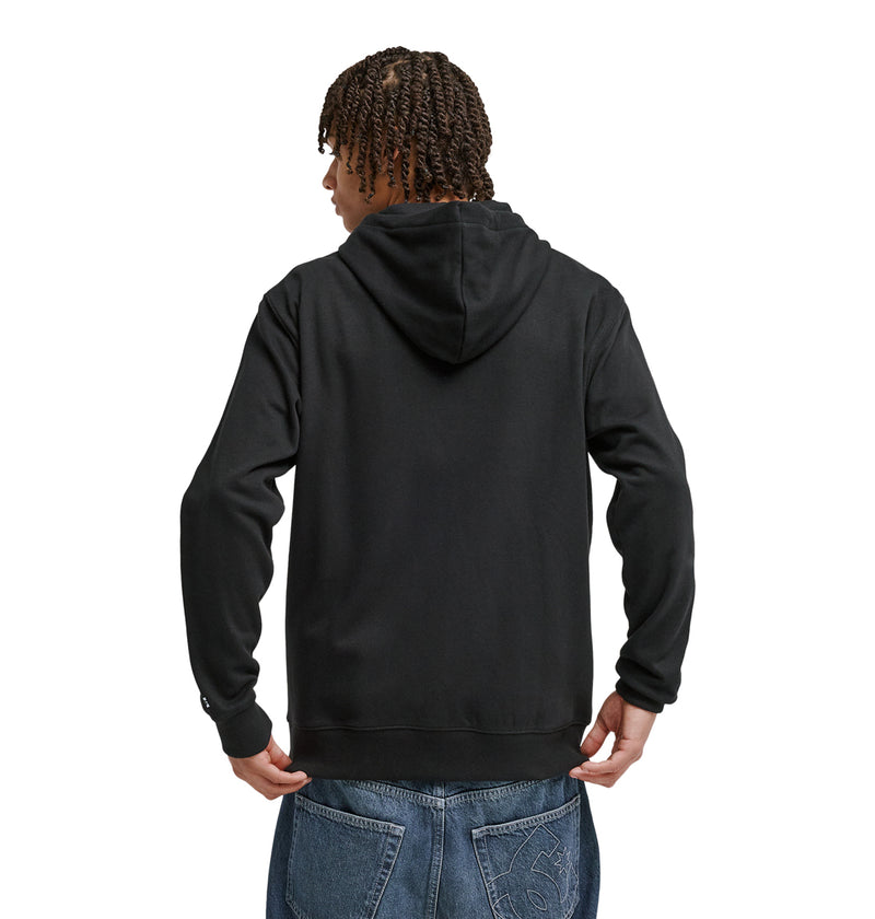 A person with braided hair is seen from the back wearing the Reebok Lorion Zh black hoodie and blue jeans with a subtle back pocket design, standing against a white background.