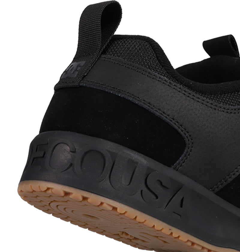 Close-up of the heel of a black DC Shoes Men's Lynx OG, featuring a textured tan sole, "DCUSA" embossed on the midsole, and a black pull tab—an iconic favorite among skateboarders.