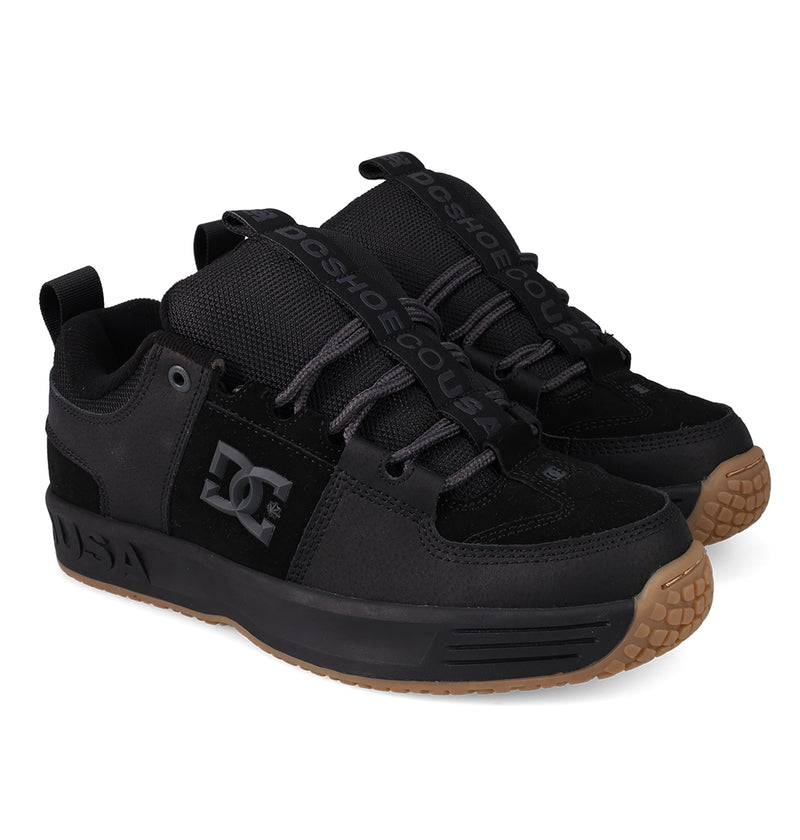 A pair of DC Shoes Men’s Lynx OG skate shoes with black uppers, gum rubber soles, black laces, “DCSHOECOUSA” on the tongue, and a chunky design with DC logo on the side—an iconic DC Team favorite for skateboarding.
