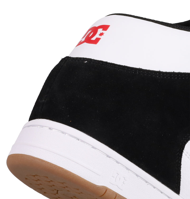 Close-up of the heel on Men's Manteca 4 Hi Shoes by DC Shoes, featuring a black and white design with a gum sole. A red DC Shoes logo pops on the white section, showcasing its vintage high-top basketball sneaker style.