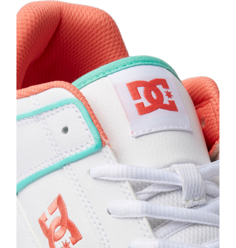 Close-up of DC Shoes Men's Manteca 4 SE sneaker in white, with an orange logo, orange inner lining, turquoise trim, and white laces. DC Shoes branding is visible on the tongue and side.